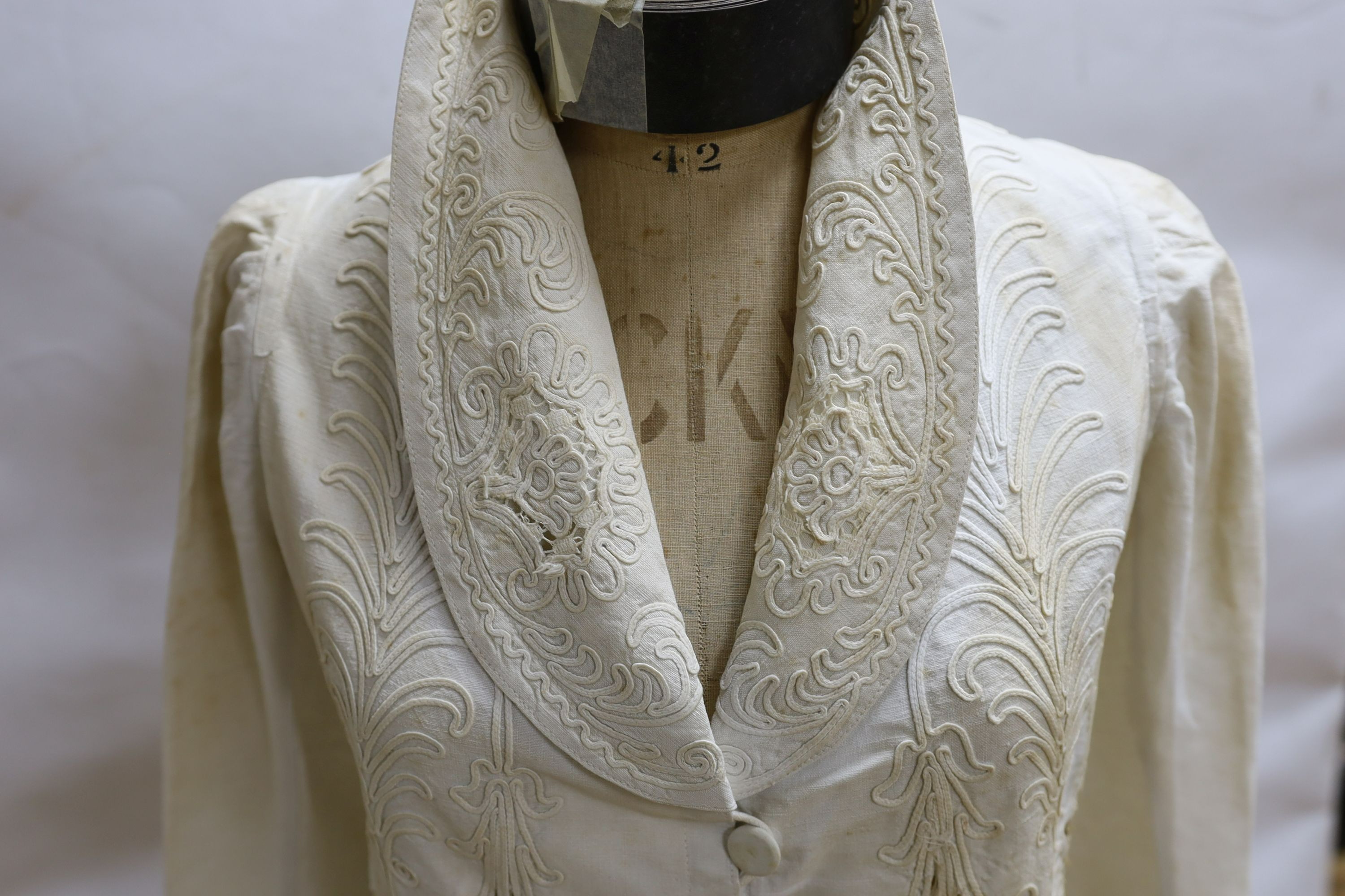 An Edwardian white/cream linen lady's coat with cut work detail and unusual button detail to the back
